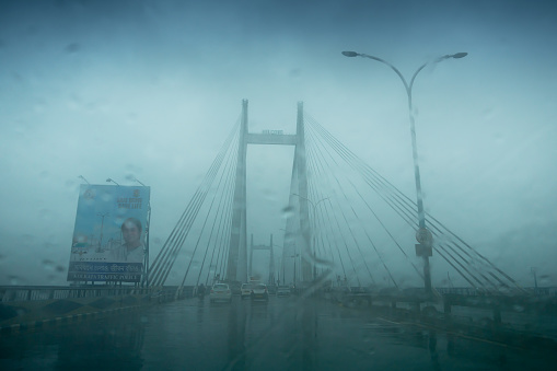 Howrah, West Bengal, India - 17th August 2019 : Image shot through raindrops falling on car windshield , wet glass, 2nd Hoogly bridge. Monsoon stock image.