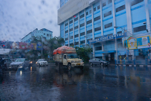 Kolkata, West Bengal, India - 25th September 2019 : Image shot through raindrops falling on wet glass, cars waiting in traffic signal - monsoon stock image of Kolkata (formerly Calcutta) city ,