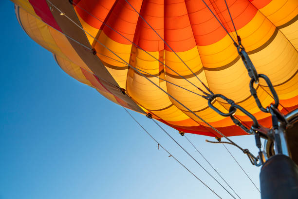 mongolfiera che vola nel cielo blu con paracadute in tessuto di colore arancione aperto e le corde agganciate con il cesto. divertimento e felicità. un'esperienza di volo rilassante. - cappadocia hot air balloon turkey basket foto e immagini stock