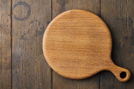 Wooden round cutting board mockup on wood background. Chopping board. Rustic tableware for kitchen and cooking. Timber utensil. Horizontal, top view, copy space