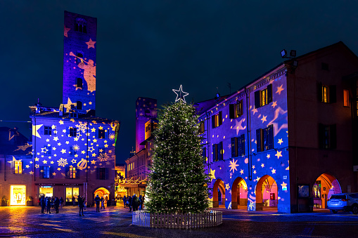 Alba, Italy - December 07, 2020: Illumination show and Christmas tree on town square in evening in Alba - capital town of Langhe area, famous for its white truffles and wine production.