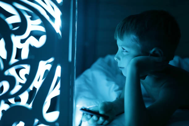 istock Boy switches color of lamp from remote control 1347015273