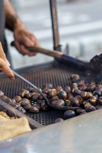 istock Man roasting chestnuts at street stall using metal utensils 1347017926