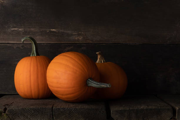 istock Three pumpkins on wooden background 1347020388