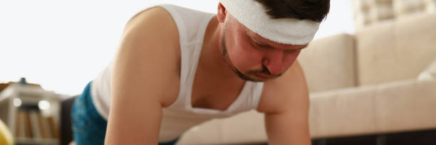 мужчина выполняет упражнения на ковре квартиры - back and forwards стоковые фото и изображения