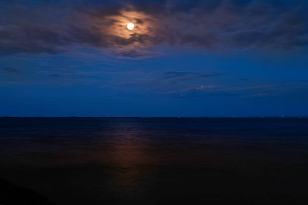 istock Seascape with full moon, dramatic clouds, blue night sky, and dark ocean water 1347021337