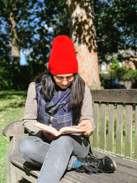 istock Young woman is reading book in a park 1347021451