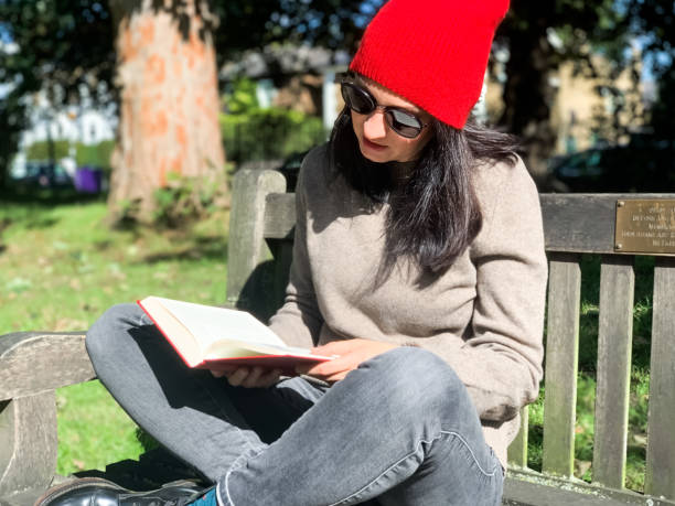istock Young woman is reading book in a park 1347021461