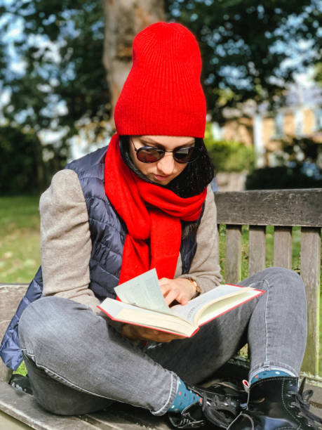 istock Young woman is reading book in a park 1347021521