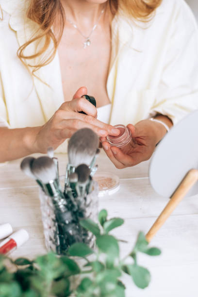 istock A set of makeup brushes, a mirror and decorative cosmetics on a white table.Blurry female hands in the background open the tube.Beauty concept. 1347021523