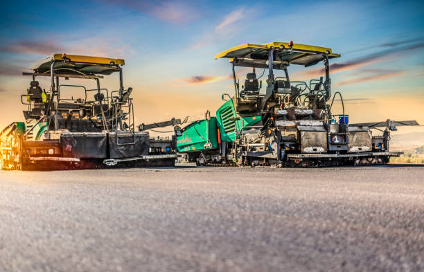 Asphalt paver machines working at sunset
