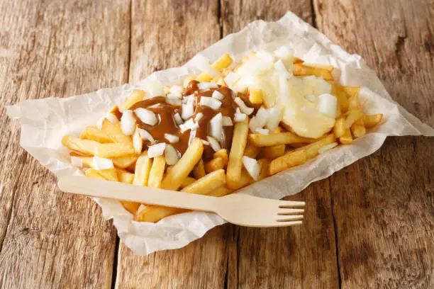 Photo of Dutch patatje oorlog means war chips and is a tasty combination of French fries, mayo, raw onions and Indonesian sauce сloseup in the plate. Horizontal