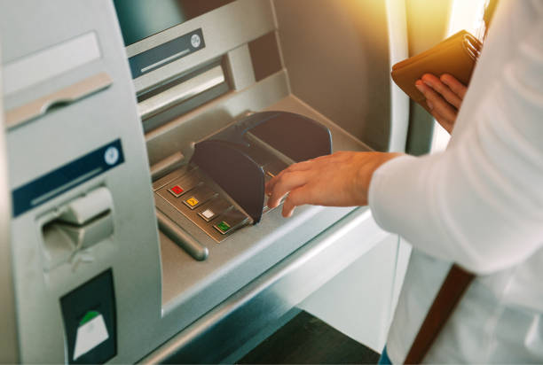 Woman pressing key pin code holding wallet on generic ATM Woman using ATM holding wallet an pressing the PIN security number on the keyboard automatic teller machine bank teller stock pictures, royalty-free photos & images