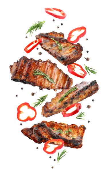 Delicious grilled meat and other ingredients falling on white background