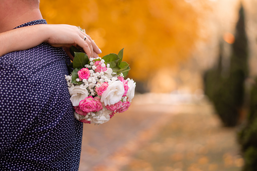 a bouquet of flowers in the hands of a girl hugging the groom. on an autumn background. fall postcard. copy space