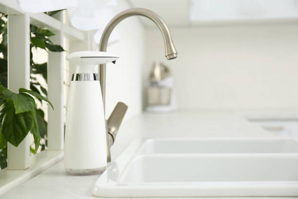 istock Modern automatic soap dispenser near sink in kitchen. Space for text 1347031201