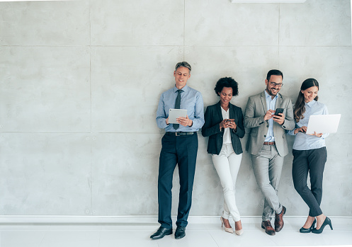 Group of business people using digital devices working together in a modern office