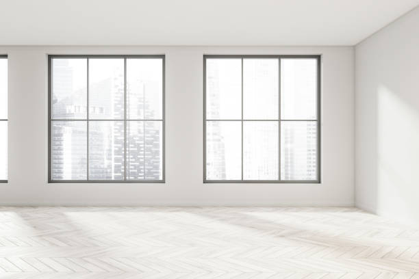 istock Empty white room space with light wood floor and windows 1347032387