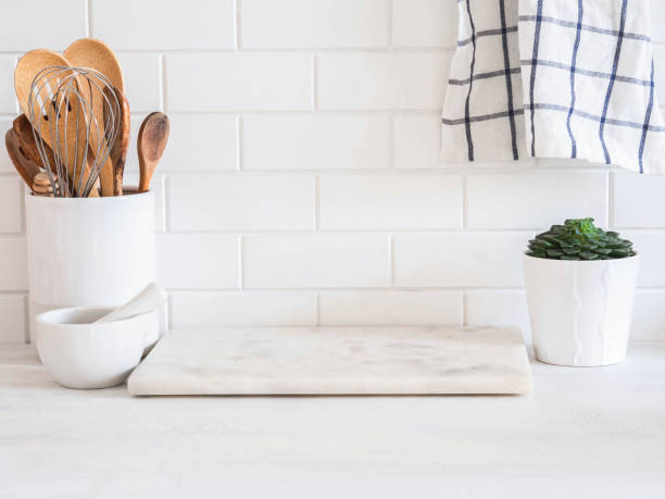 istock Stylish white kitchen background with kitchen utensils standing on wood countertop near white wall tiles 1347032702
