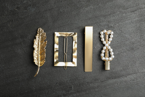 Beautiful different hair clips on black stone table, flat lay