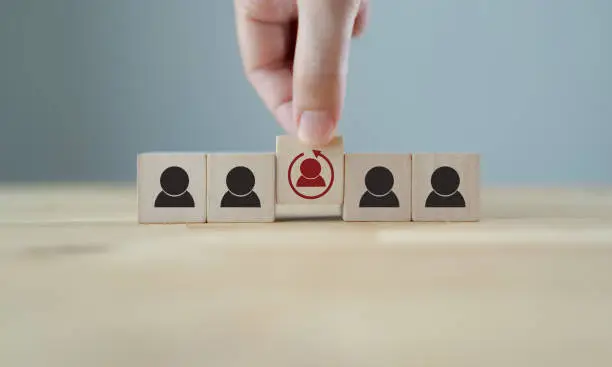 Photo of Re-skill concept to training employees on an entirely new set of skills for business growth and digital transformation. Man holds wood cube with re-skill icon on many staff icon symbol;  Copy space.