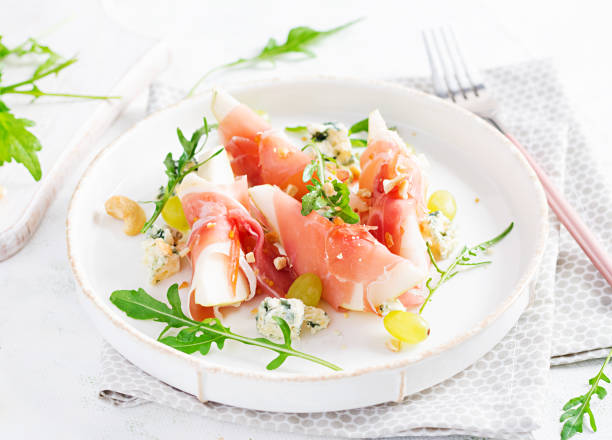 istock Appetizer with pear, blue cheese and prosciutto ham for holidays on a white plate. 1347038801