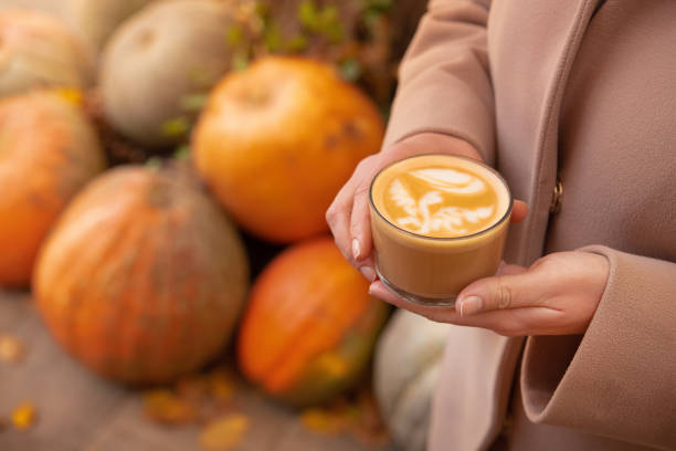 istock Woman with coffee cup on a pumpkin background 1347039838
