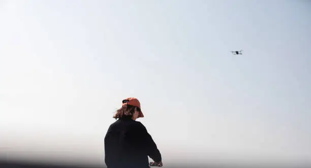 A candid photo of woman with flying drone in the sky.