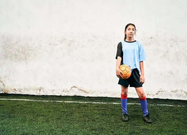Photo of Confident girl soccer player with ball at indoor field