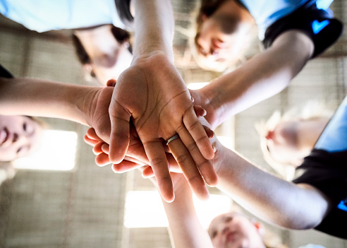 Group of businesspeople forming a circle with their hands in an office at work. Colleagues having fun and making a shape with their hands together. Coworkers showing support and motivation for each other