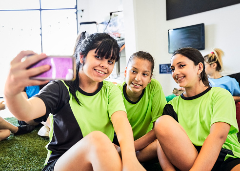 Soccer girl taking selfie with friends on indoor court