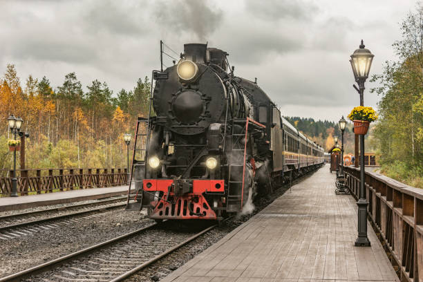 Retro steam train departs from the station wooden platform. Retro steam train departs from the station wooden platform at cloudy autumn evening. steam train stock pictures, royalty-free photos & images
