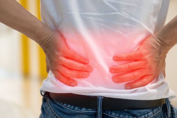 man's hands on his back with red spot as suffering on backache. male person sick from lower back pain from herniated or slipped discs,degenerative, sacroiliac joint, spinal stenosis, pancreatic cancer - human spine posture back backache imagens e fotografias de stock