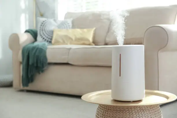 Photo of Modern air humidifier on table in living room. Space for text