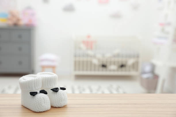 Small baby booties on wooden table in room. Space for text