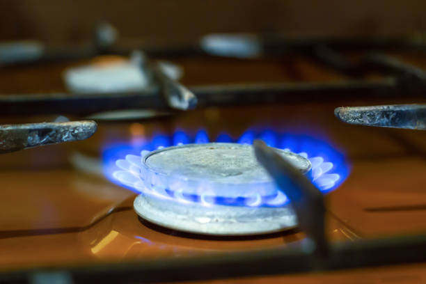 Old gas stove burner in domestic kitchen closeup. Low blue flame for cooking in apartment close up. Detail of oven fire on counter, soft focus
