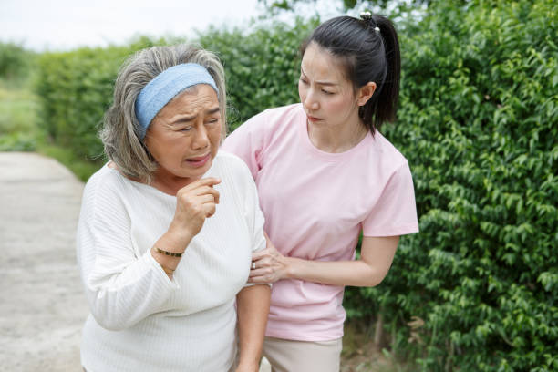 asian young daughter caring for sick senior mother To suffering illness or cough at home . old mom suffering from illness has an adult caregiver woman to take care stock photo