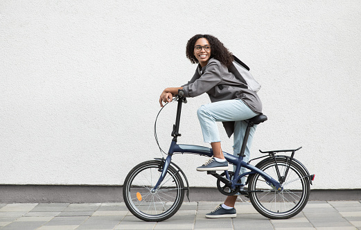 Smiling african-american woman riding a bike looking up outdoor. Travel, people and active lifestyle concept