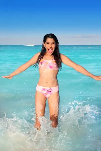 Photo of Latin teen girl jumping on Caribbean beach shore