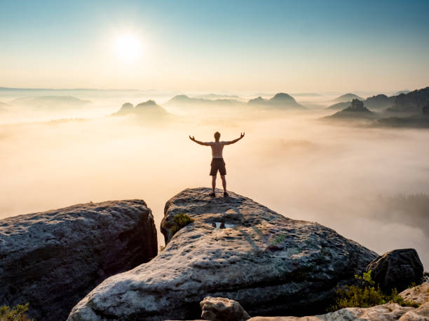 istock Happy trail runner at rocky view edge raised arms to sun greeting. 1347056536