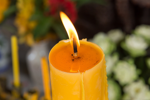 an orange candle burns in the dark on a black background. The concept of memory and sorrow.