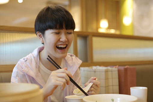 An Asian teenage girl is enjoying 'xiao long bao' (soup dumpling) in Chinese restaurant.