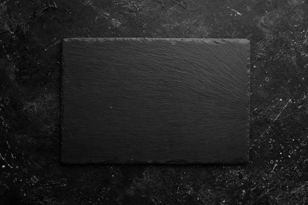 istock Black stone slate plate on a black stone background. Free copy space. Top view. 1347061747