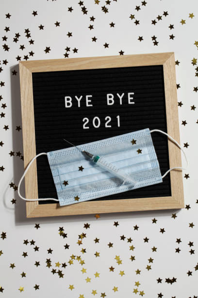 istock black letter board with text BYE BYE 2021 with small stars, syringe and mask on white background. Happy new ear 2022 concept. 1347062313