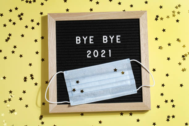 istock black letter board with text BYE BYE 2021 with small stars and mask on yellow background. Happy new ear 2022 concept. 1347062428