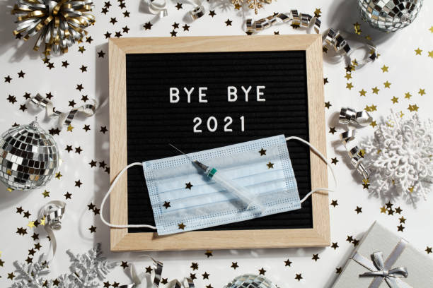istock black letter board with text BYE BYE 2021 with decoration, syringe and mask on white background. Happy new ear 2022 concept. 1347062429