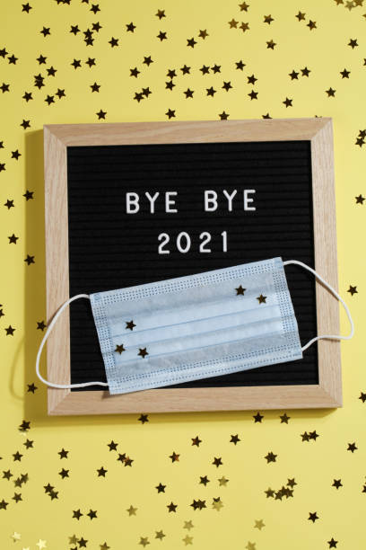istock black letter board with text BYE BYE 2021 with small stars and mask on yellow background. Happy new ear 2022 concept. 1347062518