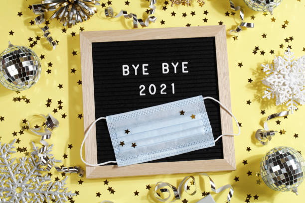 istock black letter board with text BYE BYE 2021 with decoration and mask on yellow background. Happy new ear 2022 concept. 1347062647