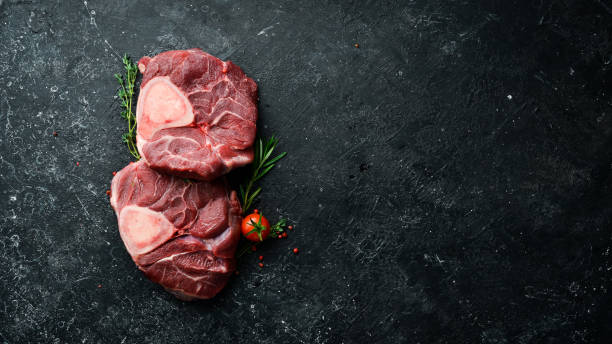 Osso buco Veal steak with rosemary and spices. On a black background. Top view. Osso buco Veal steak with rosemary and spices. On a black background. Top view. ossobuco stock pictures, royalty-free photos & images