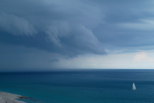 A lone sailboat races ahead of an approaching thunderstorm on the Atlantic Ocean in Palm Beach, Florida.